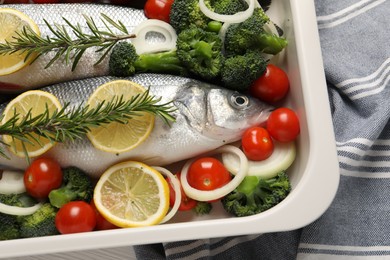 Photo of Raw fish with vegetables and lemon in baking dish on table, top view