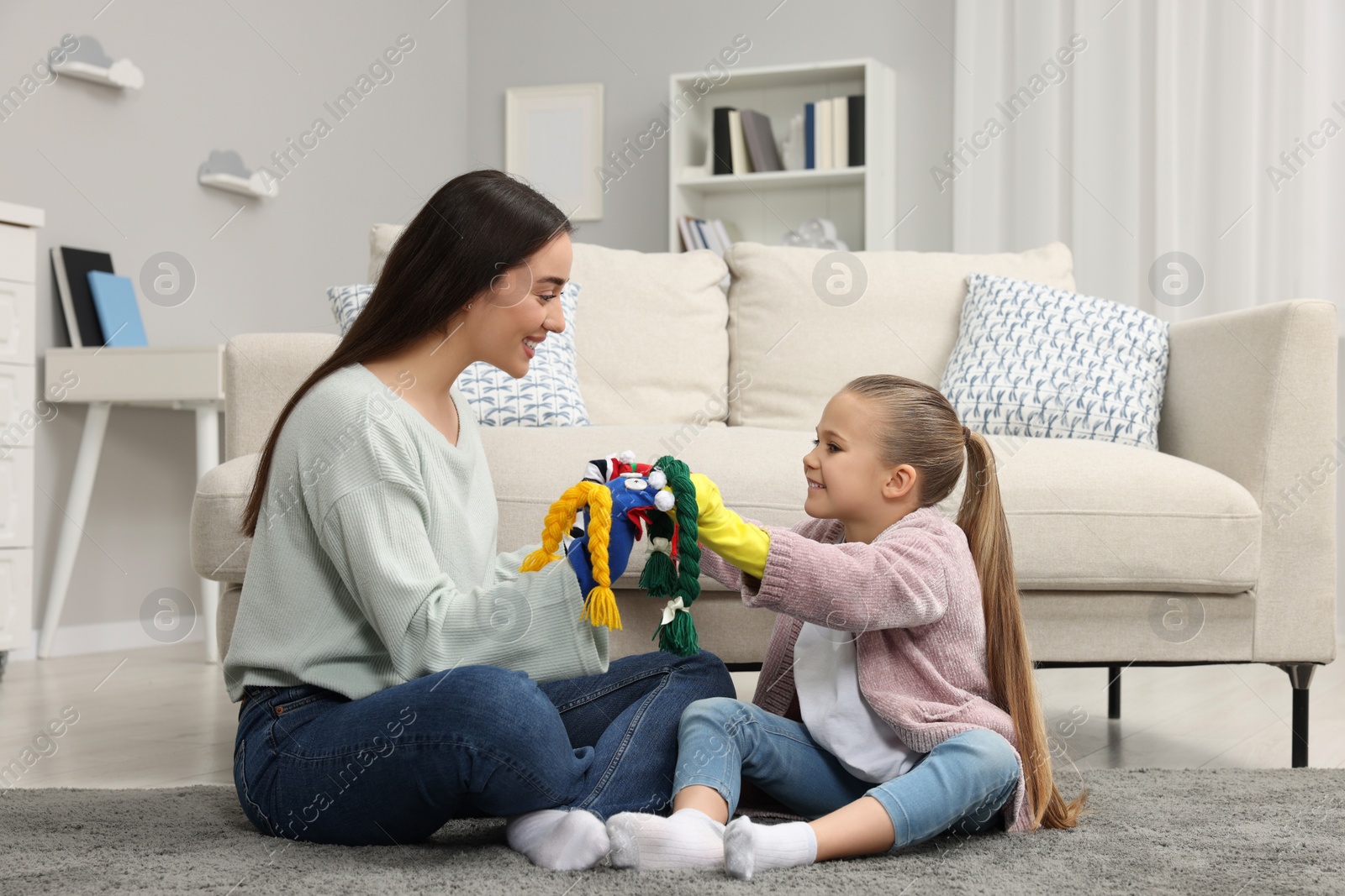 Photo of Happy mother and daughter playing with funny sock puppets together at home