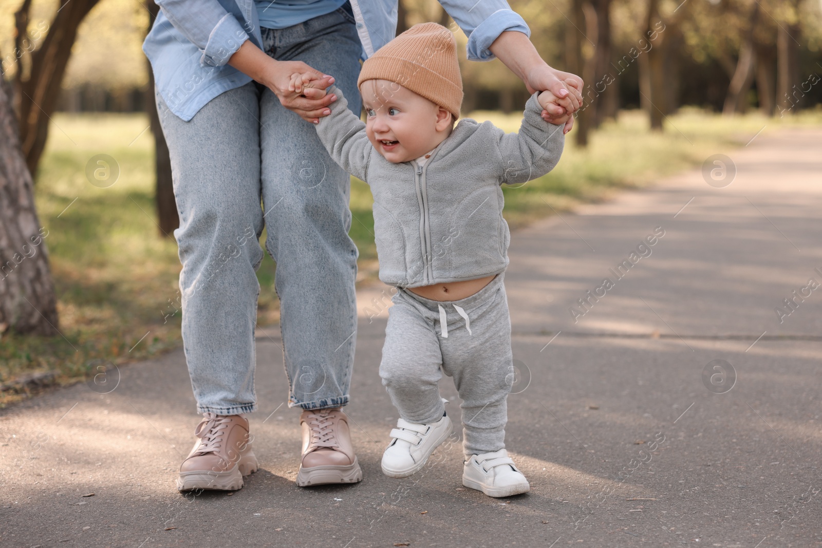 Photo of Mother teaching her baby how to walk outdoors, closeup