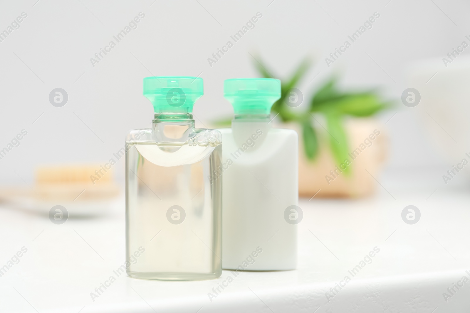 Photo of Mini bottles of cosmetic products on white table against blurred background