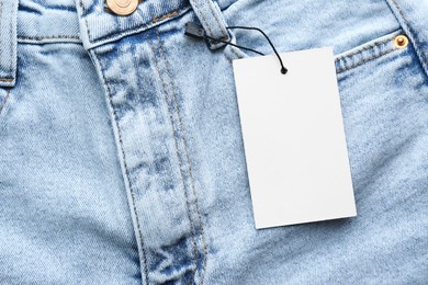 Photo of Blank tag on jeans, top view. Space for text
