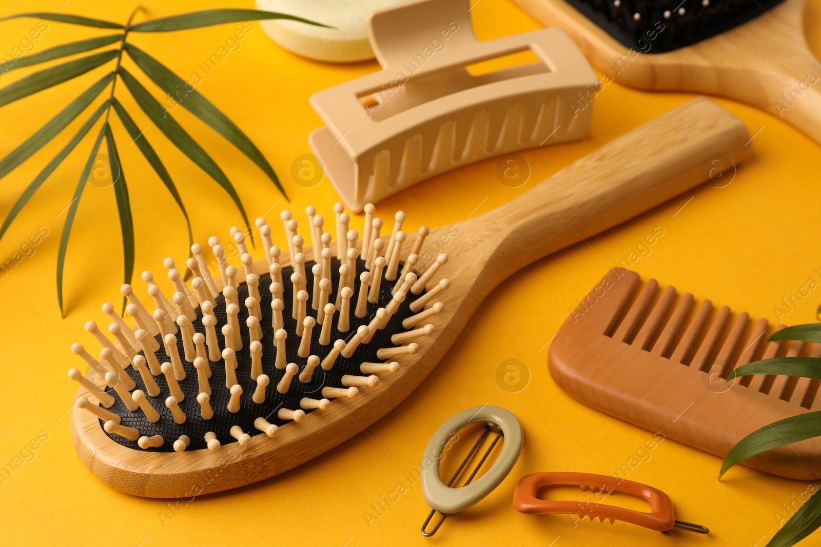 Photo of Wooden brushes, comb and different hair products on orange background