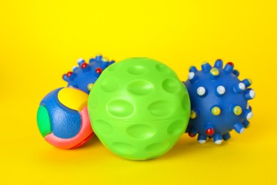 Photo of Toy balls and bone for pet on yellow background
