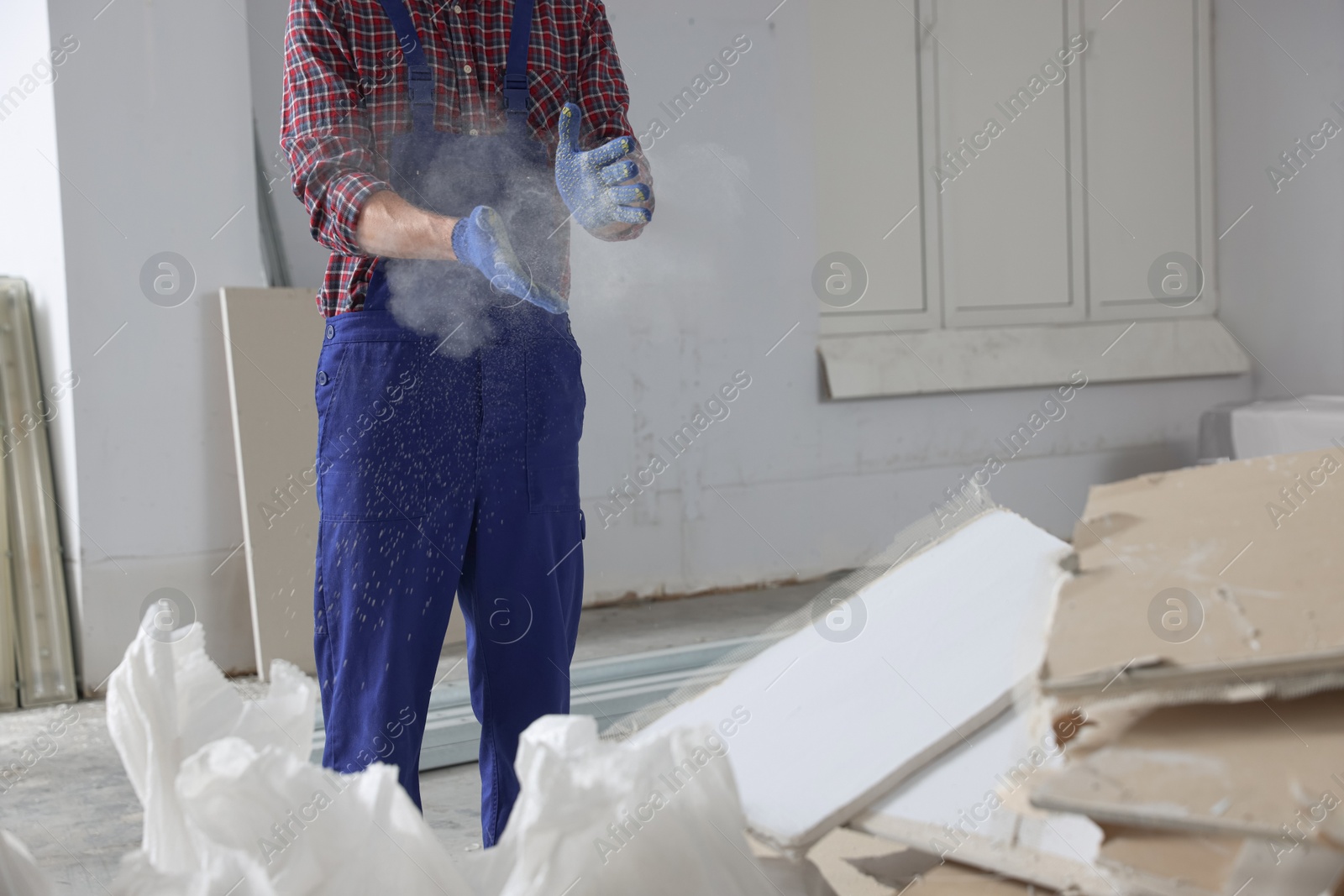 Photo of Construction worker shaking off dust from hands in room prepared for renovation, closeup