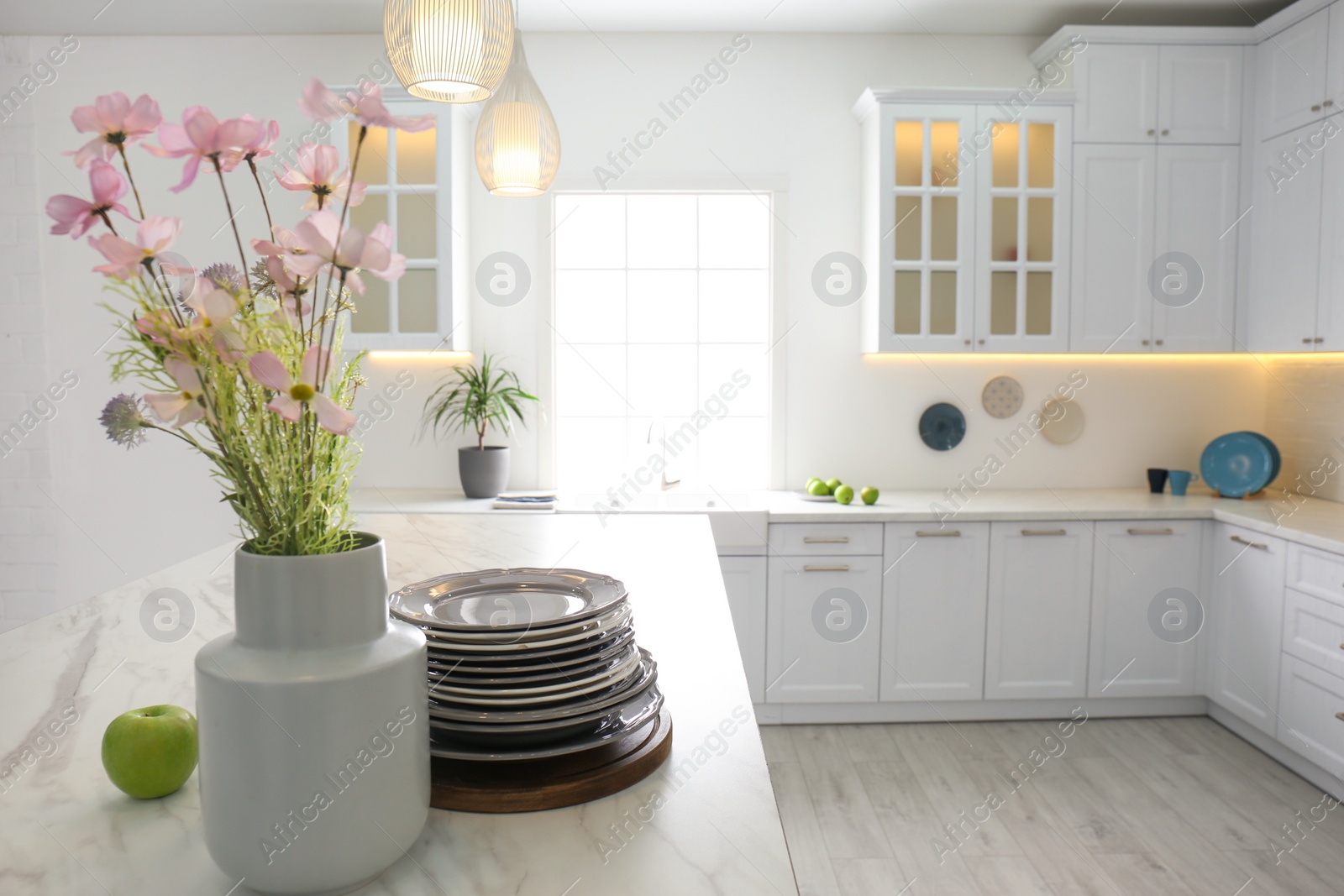 Photo of Beautiful flowers and dishware on white marble table in modern kitchen