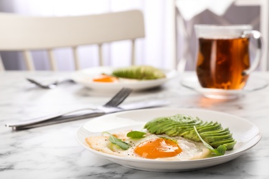 Photo of Tasty breakfast with fried egg and avocado on white marble table