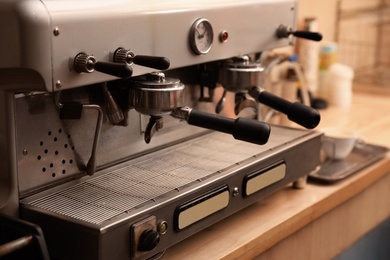 Modern electric coffee machine with portafilters on table