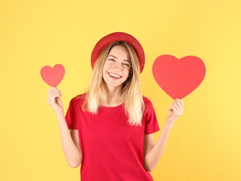 Portrait of young woman with paper hearts on color background