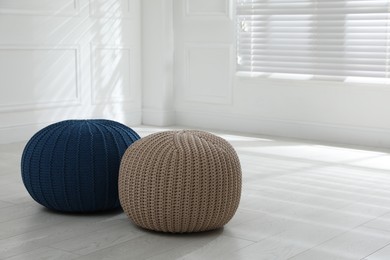 Different stylish poufs in room, space for text