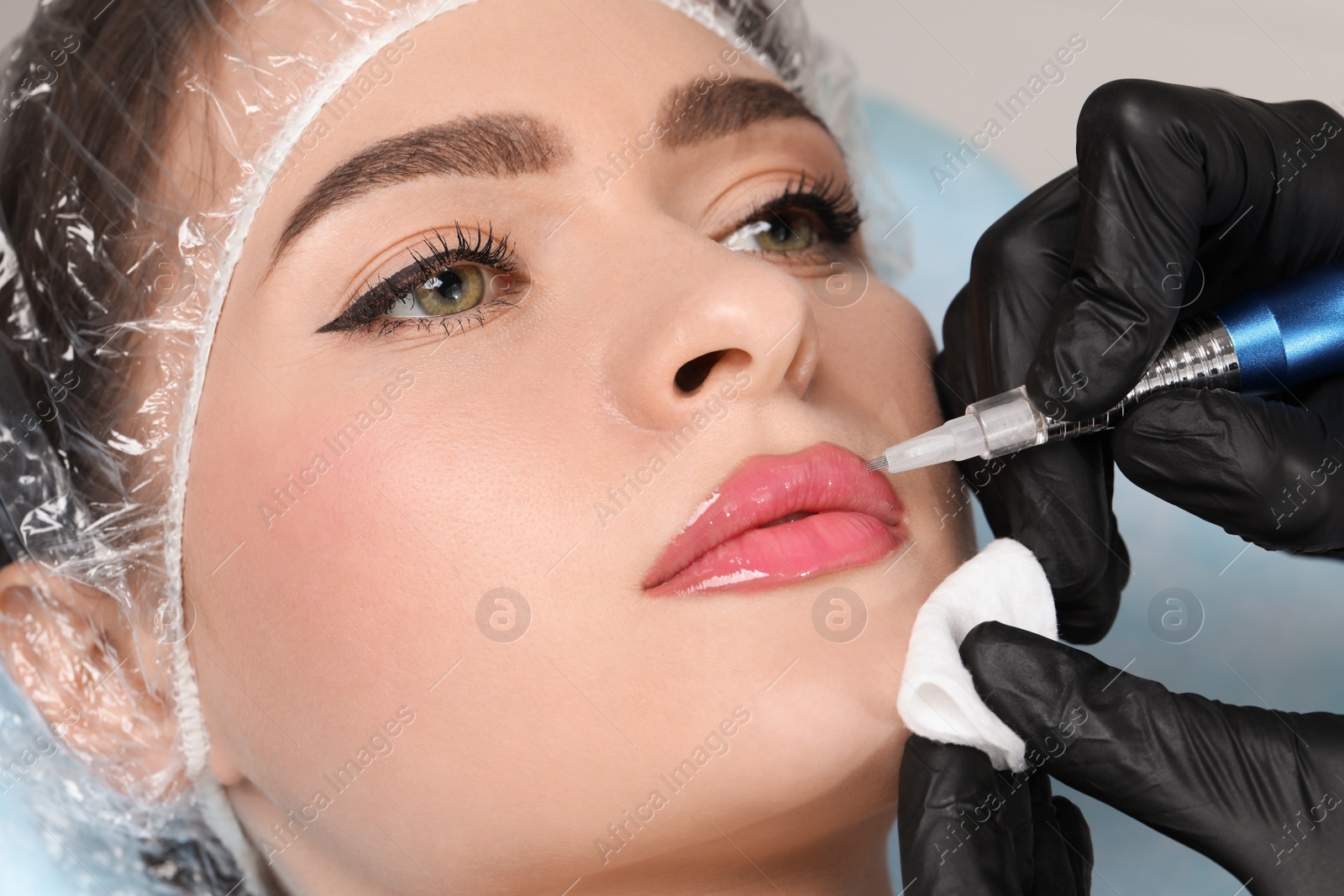 Photo of Young woman during procedure of permanent lip makeup in beauty salon, closeup