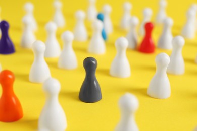 Photo of Colorful pawns on yellow background, closeup. Social inclusion concept