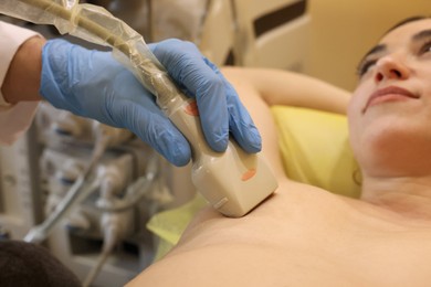 Mammologist conducting ultrasound examination of woman's breast in clinic, closeup