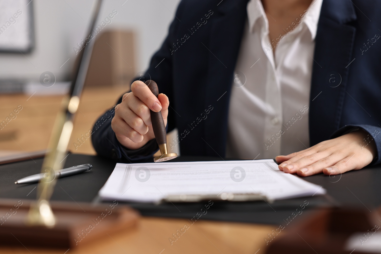 Photo of Notary sealing document at table in office, closeup