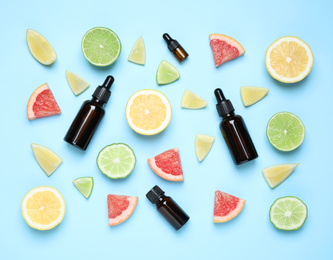 Flat lay composition with bottles of citrus essential oil on light blue background