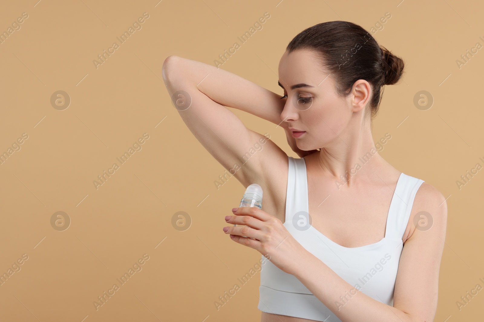 Photo of Beautiful woman applying deodorant on beige background, space for text