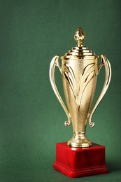 Shiny golden trophy cup on green background