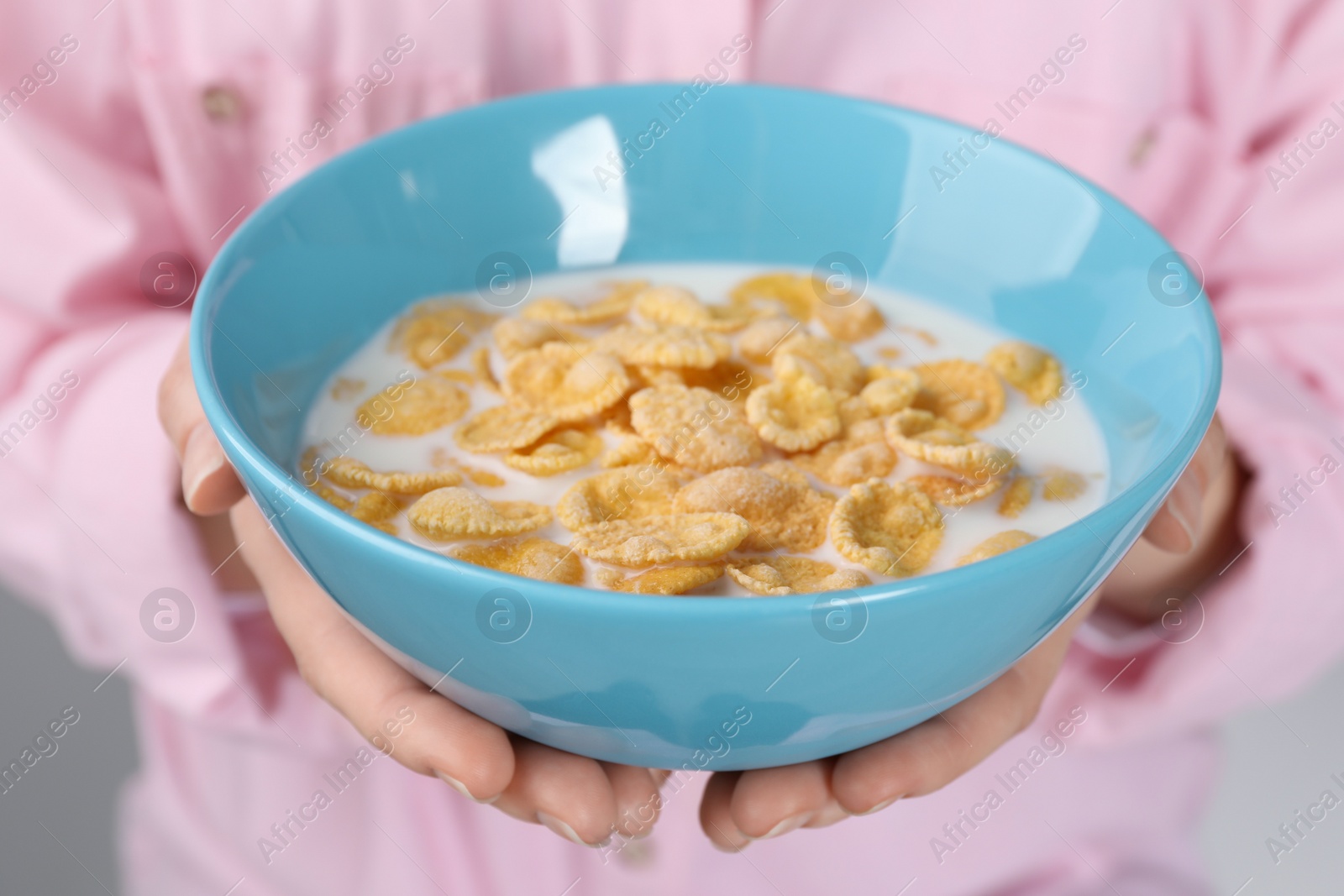 Photo of Woman holding bowl of crispy corn flakes with milk, closeup