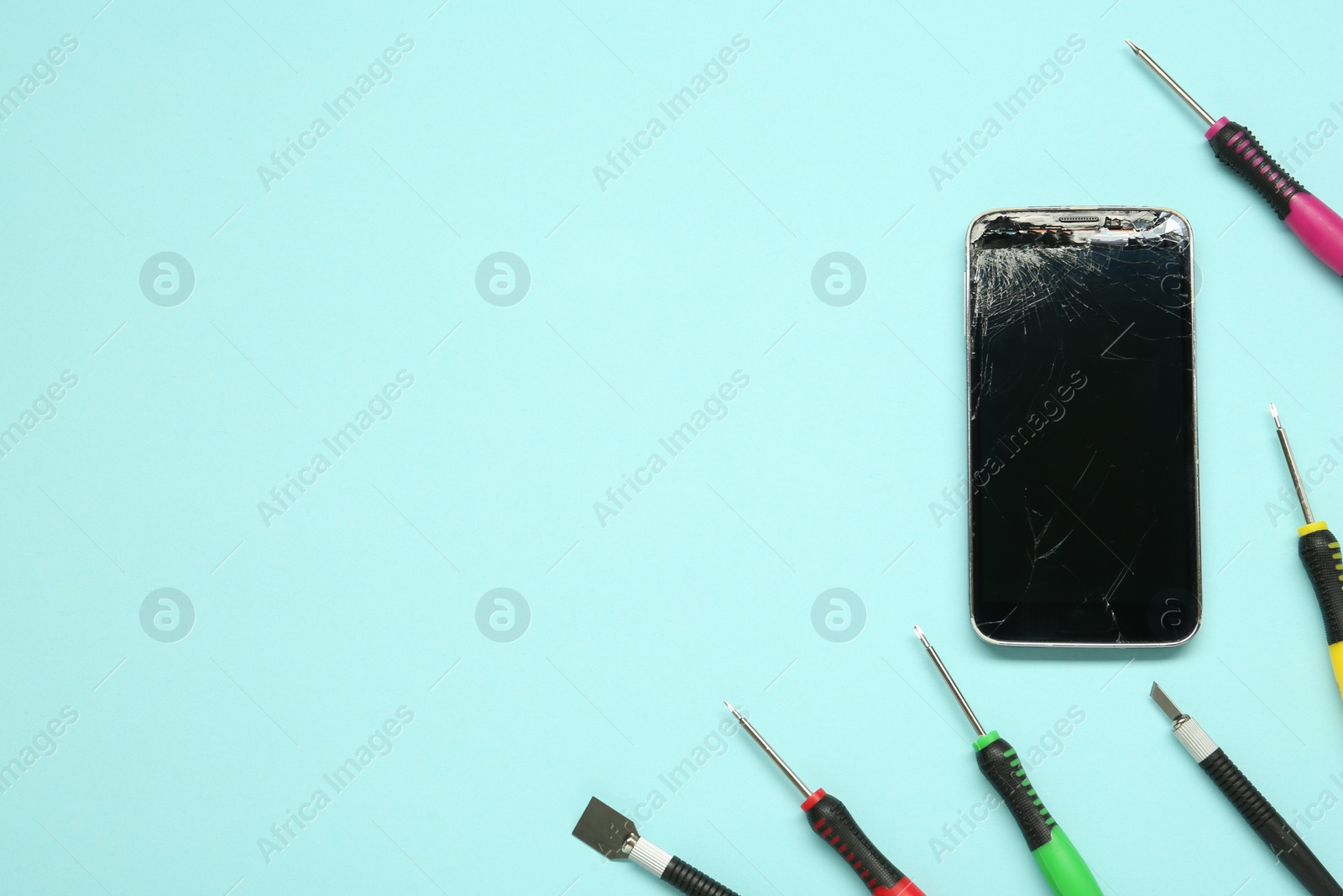 Photo of Damaged smartphone and repair tool set on light blue background, flat lay. Space for text