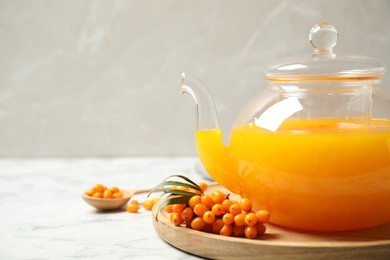 Photo of Delicious sea buckthorn tea on white marble table, closeup. Space for text
