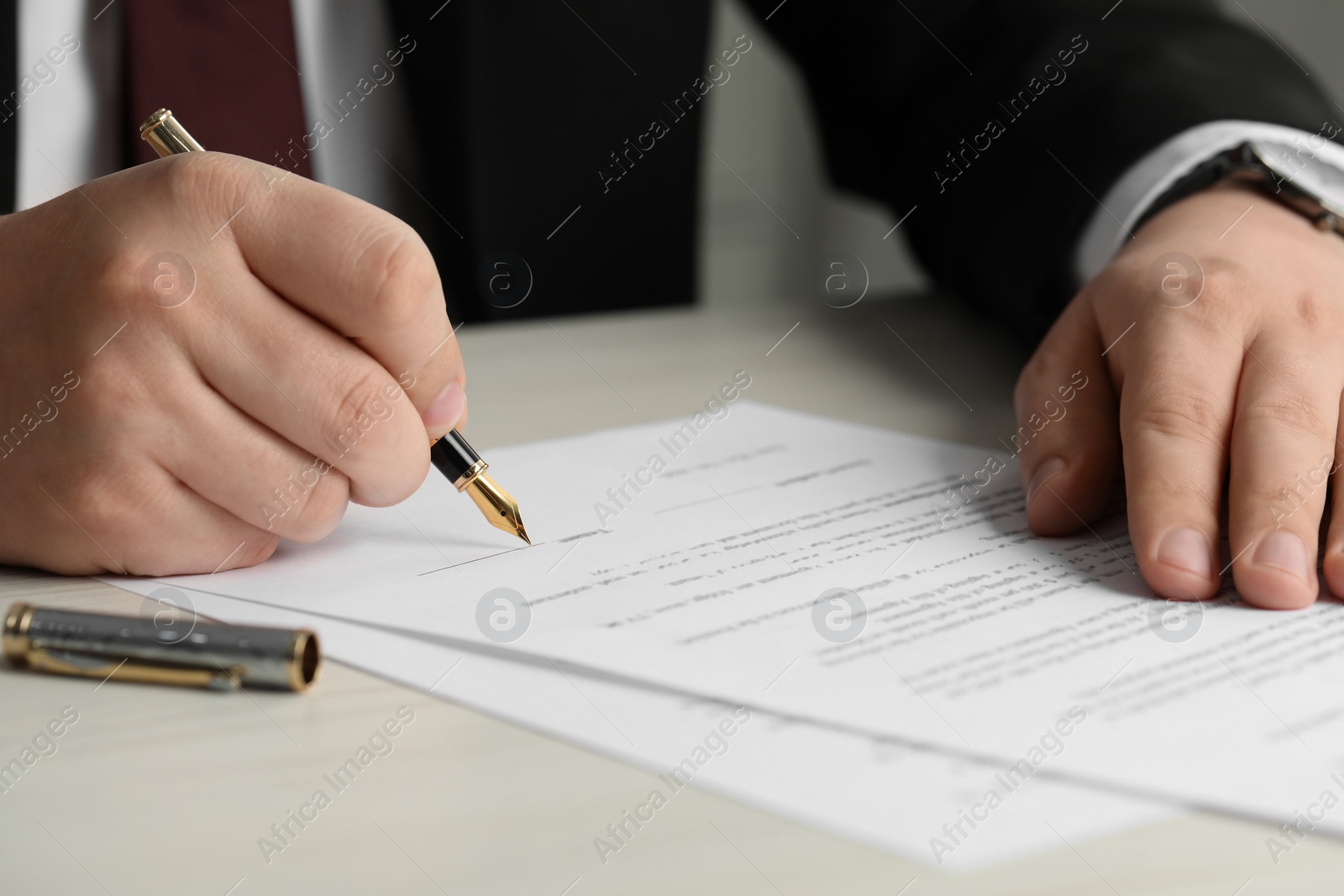 Photo of Notary signing document at wooden table, closeup