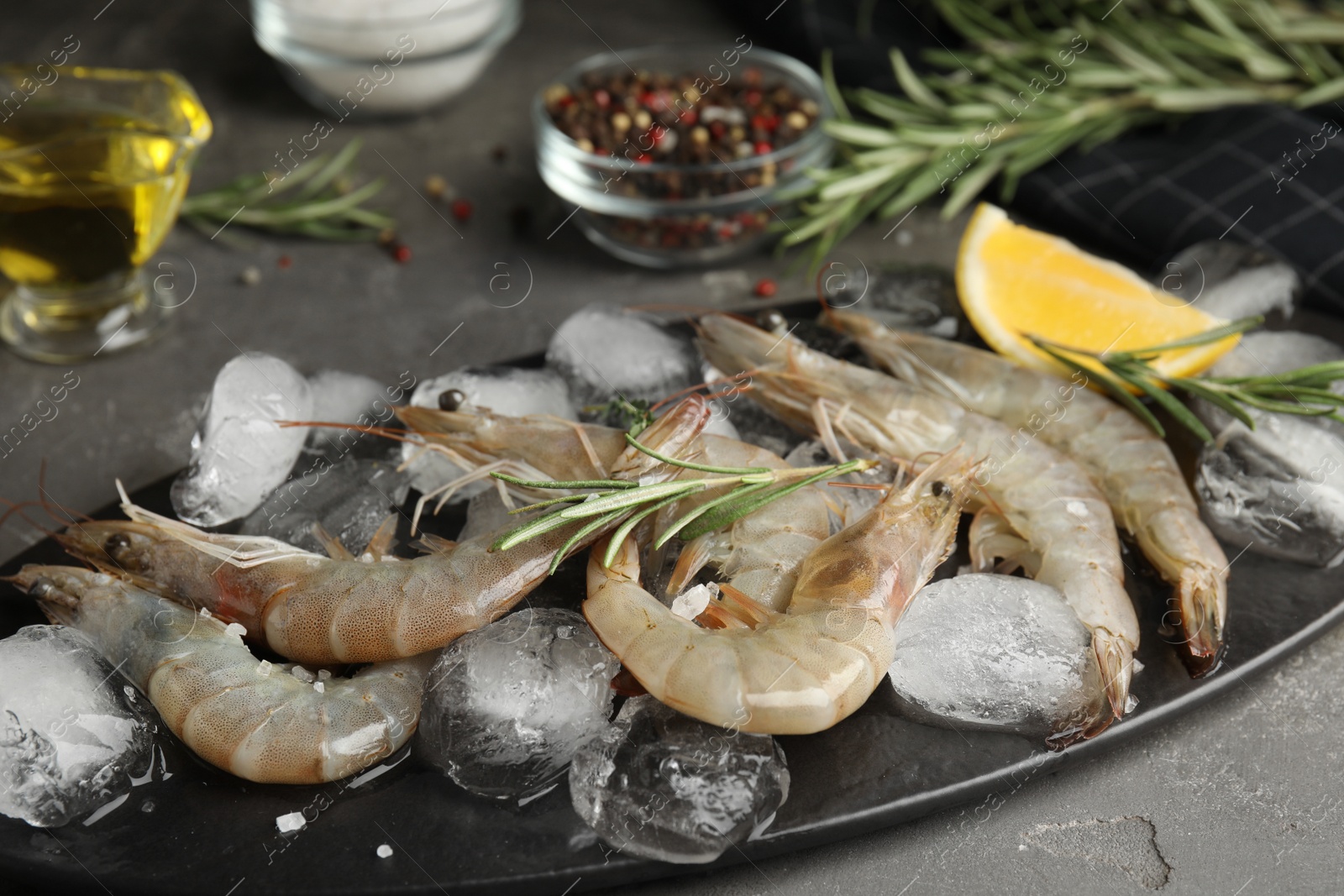 Photo of Raw shrimps with ice on grey table