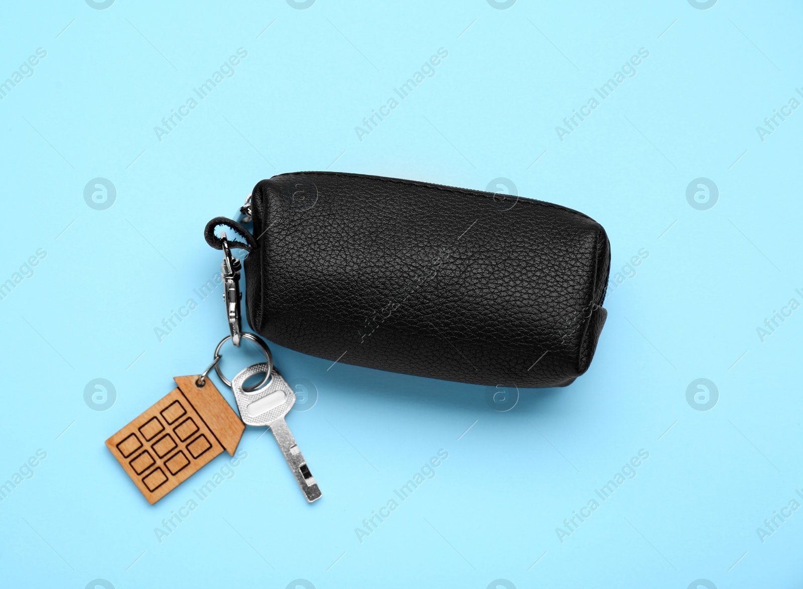 Photo of Leather case with keys on light blue background, top view