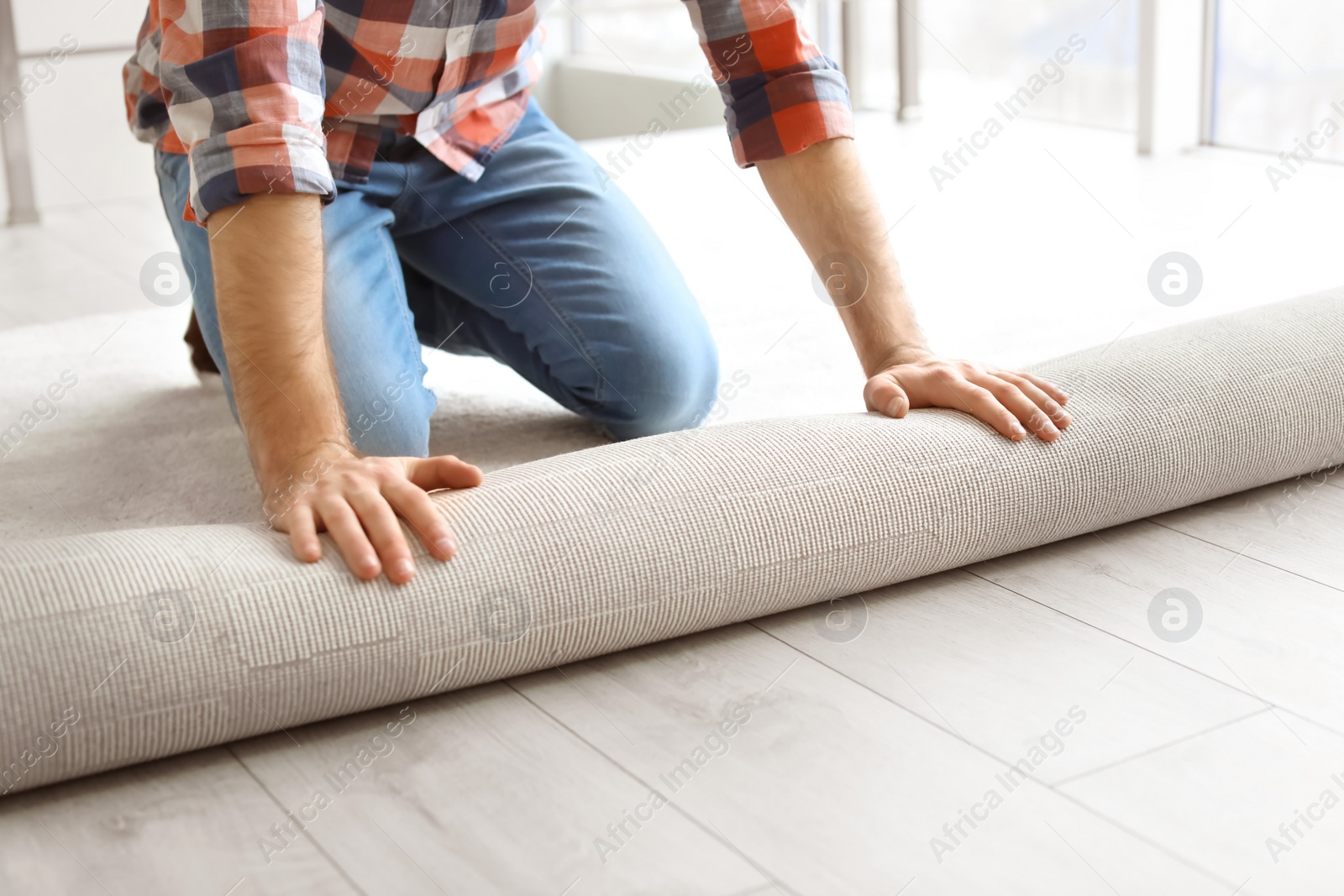 Photo of Man rolling out new carpet flooring in room