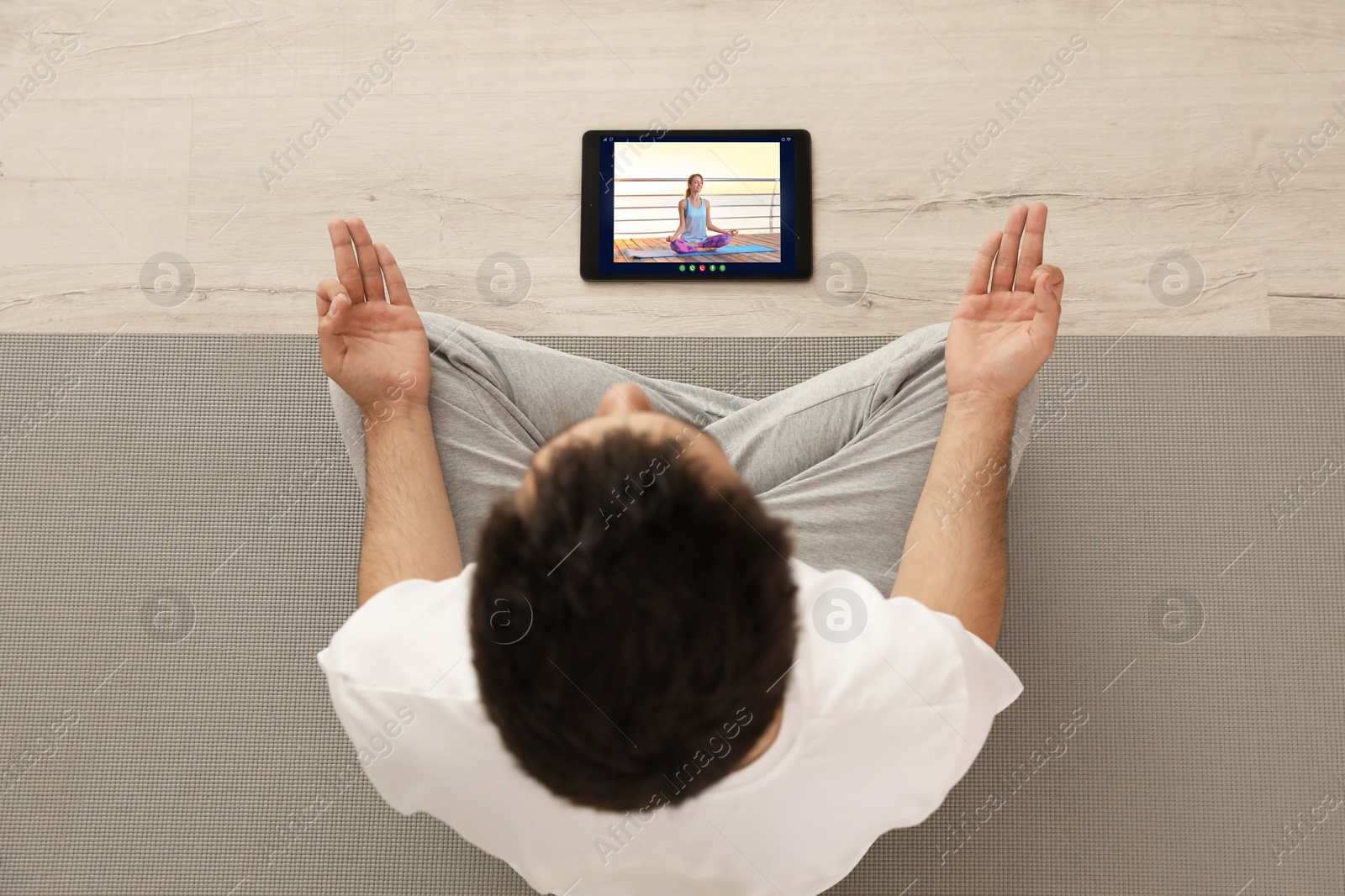 Image of Distance yoga course during coronavirus pandemic. Man having online practice with teacher via tablet at home, top view