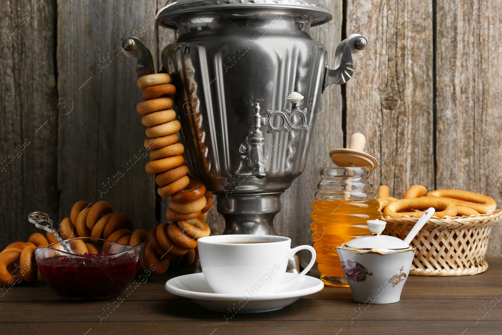 Photo of Composition with hot tea and delicious ring shaped Sushki (dry bagels) on wooden table