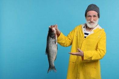 Fisherman with caught fish on light blue background, space for text