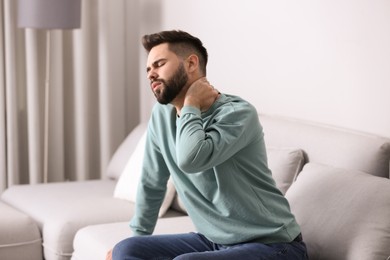 Photo of Man suffering from back pain at home. Bad posture problem