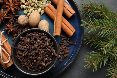 Photo of Dishware with different spices, nuts and fir branches on table, flat lay