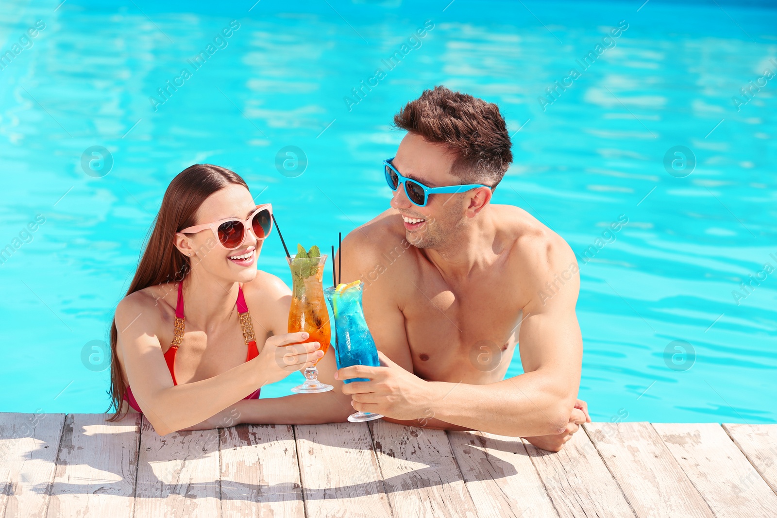 Photo of Happy young couple with cocktails in swimming pool