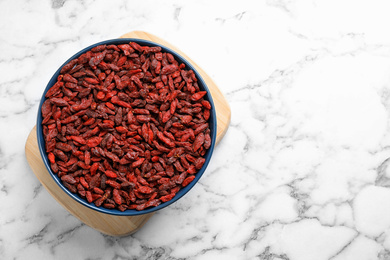 Photo of Dried goji berries on white marble table, top view. Space for text