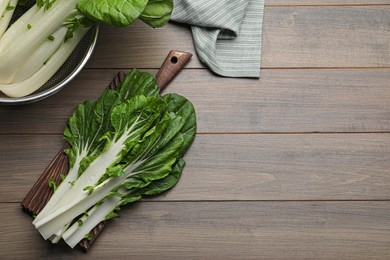 Fresh green pak choy cabbage with water drops on wooden table, flat lay. Space for text