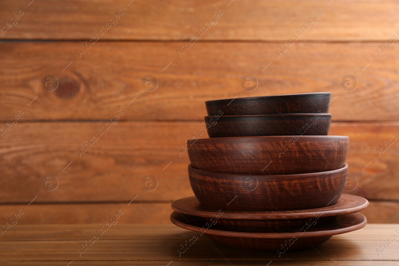 Photo of Set of clay utensils on wooden table. Space for text