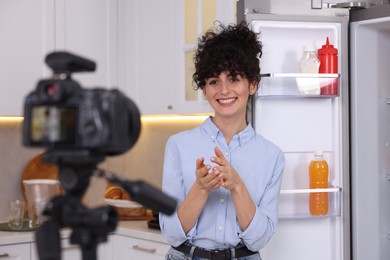 Photo of Smiling food blogger explaining something while recording video in kitchen