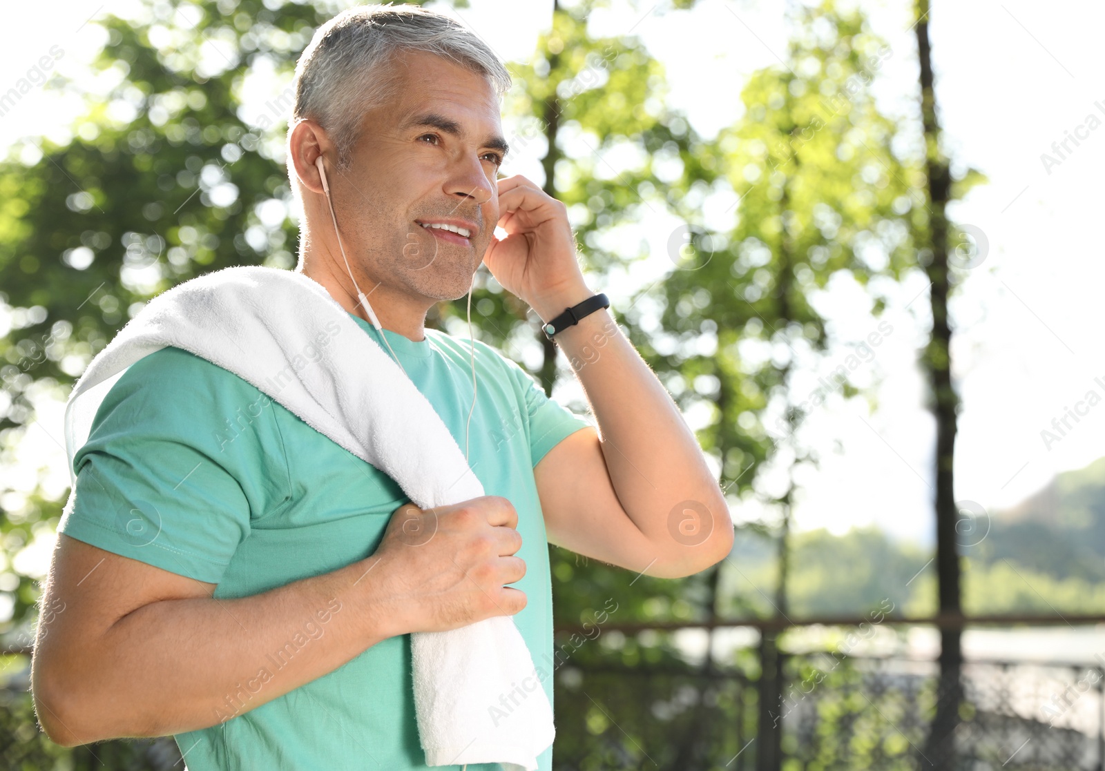 Photo of Handsome mature man listening to music in park, space for text. Healthy lifestyle