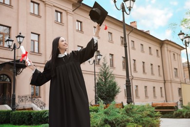 Photo of Happy student with diploma after graduation ceremony outdoors. Space for text