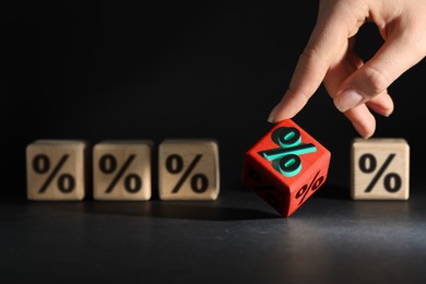 Image of Best mortgage interest rate. Woman touching red cube with percent sign on black table, closeup