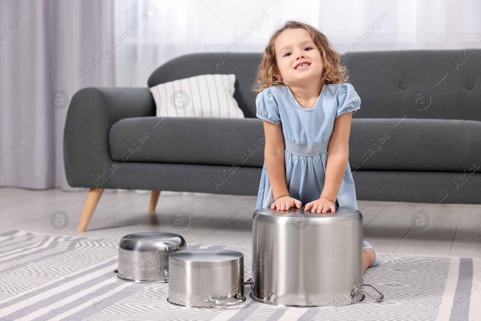 Photo of Little girl pretending to play drums on pots at home