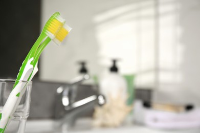 Light green toothbrushes in glass holder indoors, space for text