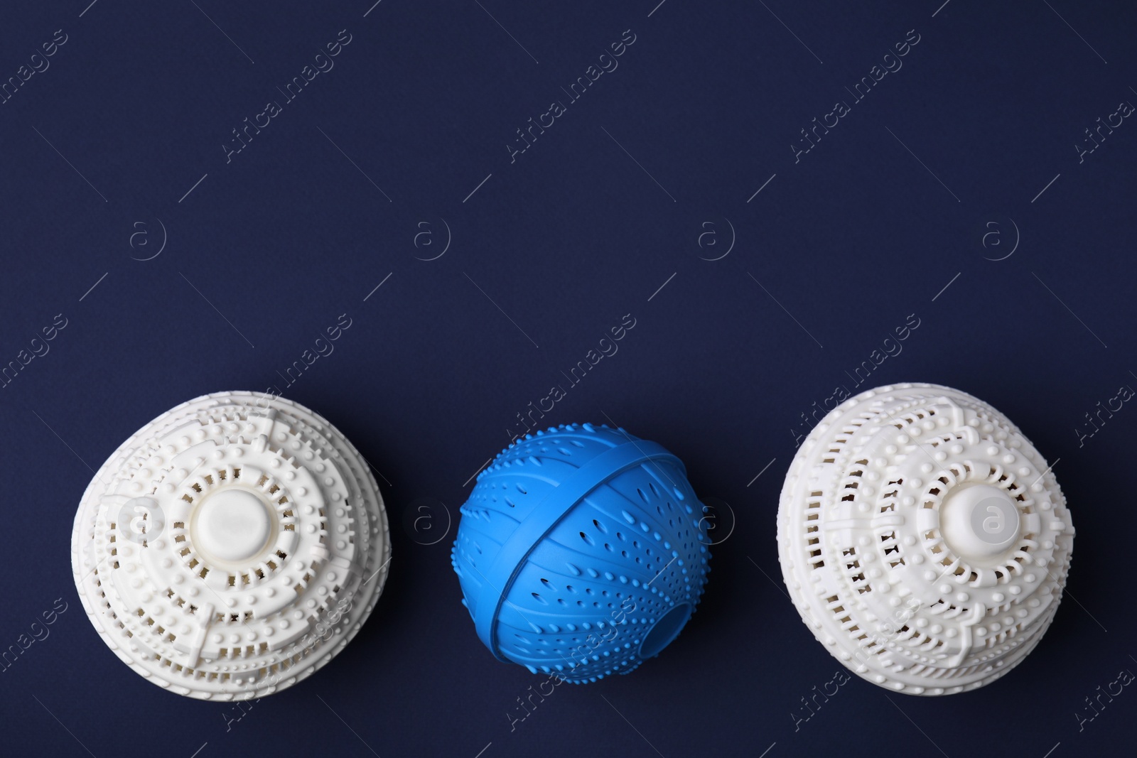 Photo of Laundry dryer balls on dark blue background, flat lay. Space for text