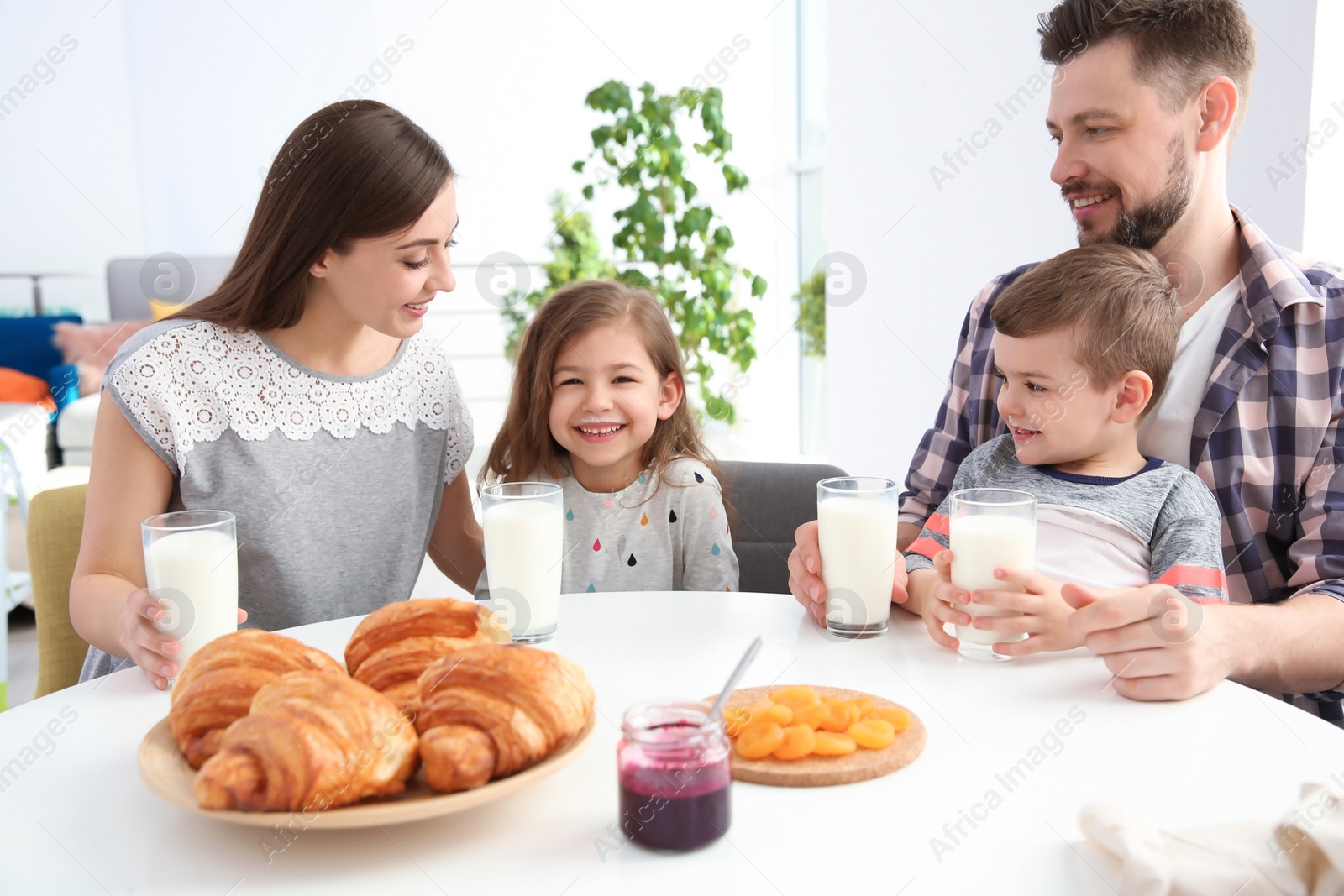 Photo of Happy family having breakfast with milk at table