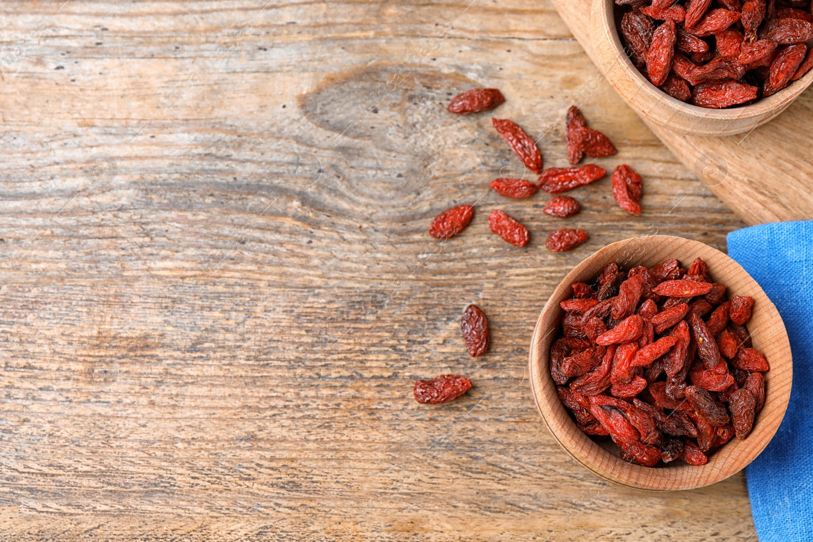 Photo of Dried goji berries on wooden table, flat lay. Space for text