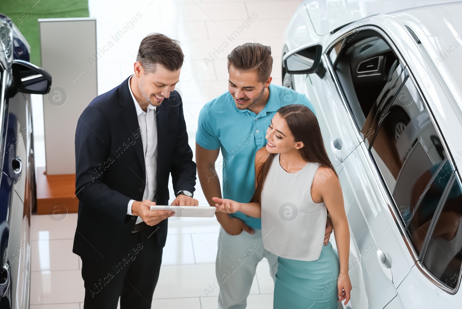 Photo of Salesman consulting young couple in car salon