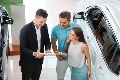 Salesman consulting young couple in car salon