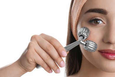 Woman using metal face roller on white background, closeup