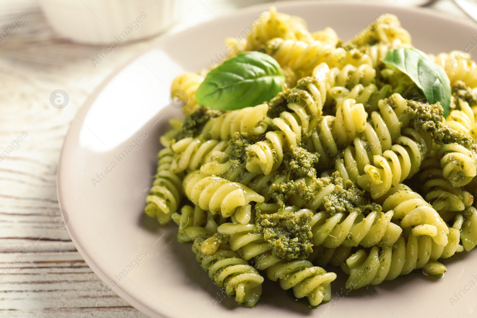 Photo of Plate with delicious basil pesto pasta on table