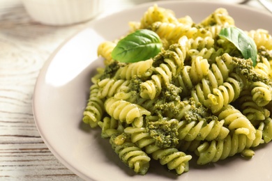 Photo of Plate with delicious basil pesto pasta on table